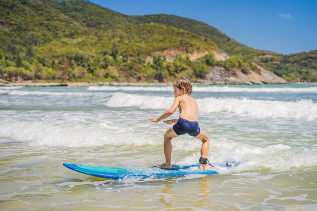 Niño sano aprendiendo a surfear en el mar o el océano