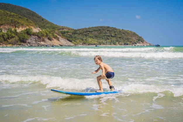 Niño sano aprendiendo a surfear en el mar o el océano