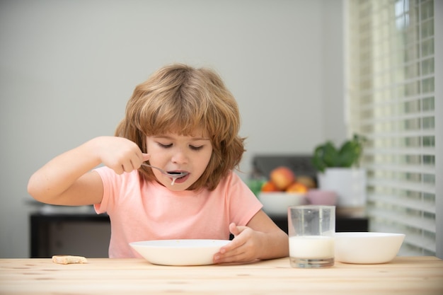 Niño sano y hambriento comiendo sopa con cuchara. Nutrición infantil.