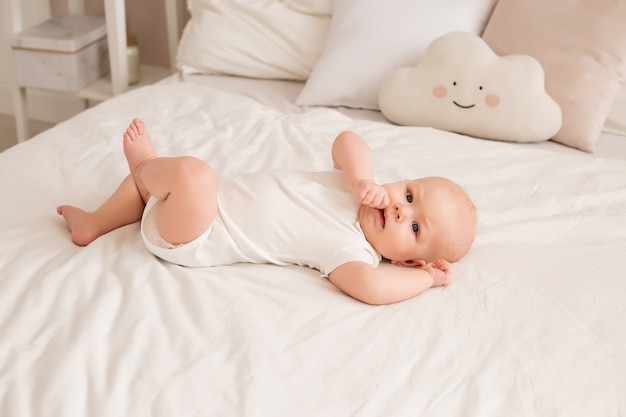 Niño sano niño sonriente en ropa blanca se encuentra en la cama vista desde arriba