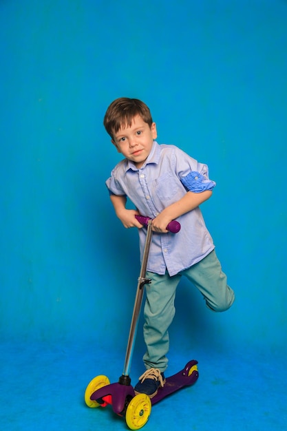 Un niño en un scooter sobre un fondo azul Un artículo sobre scooters para niños Un artículo sobre la elección de un scooter para un niño Un niño feliz Fondo azul y un niño