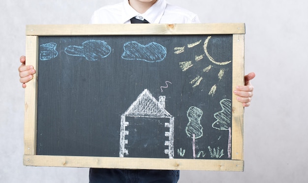 Niño de seis años con casa representada sobre una superficie de madera. De cerca