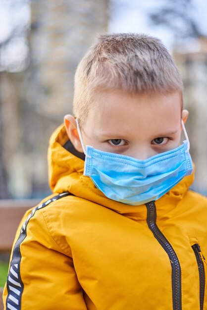 Niño de seis años con una máscara médica en una calle