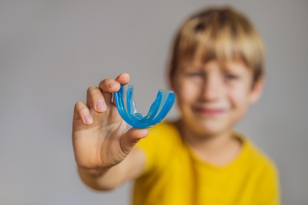 Un niño de seis años muestra un entrenador miofuncional Ayuda a equilibrar los dientes en crecimiento y la mordida correcta Desarrolla el hábito de respirar por la boca Corrige la posición de la lengua