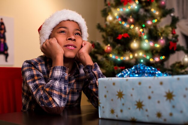 Niño sentado al lado del regalo de Navidad.