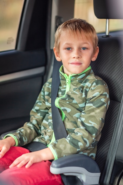 Niño sentado en un asiento elevado abrochado en el coche.