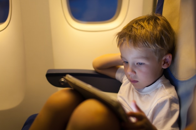 Niño sentado en el avión y usando la tableta