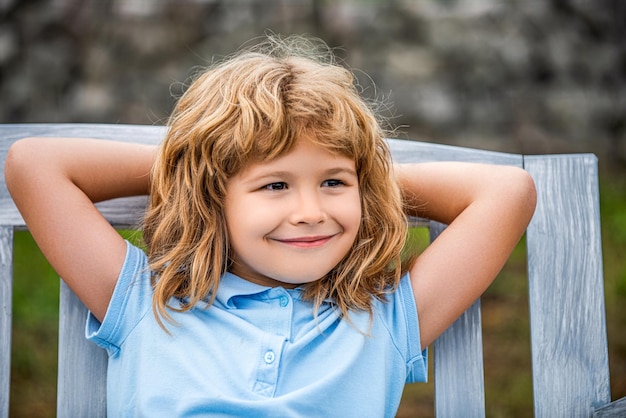 Niño sentado en el banco placer Niños al aire libre Idea de los niños y sonrisa con un niño feliz afuera Niño descansando en el parque de verano Niño relajándose en el banco después de un largo día escolar