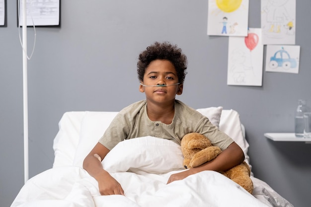 Niño sentado en la cama de un hospital