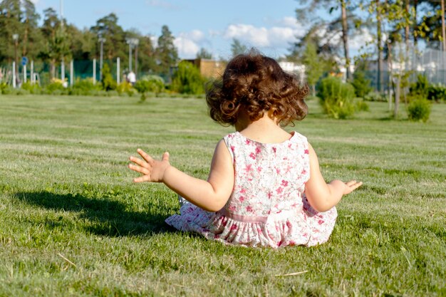 Foto un niño está sentado en el césped en un día de verano.