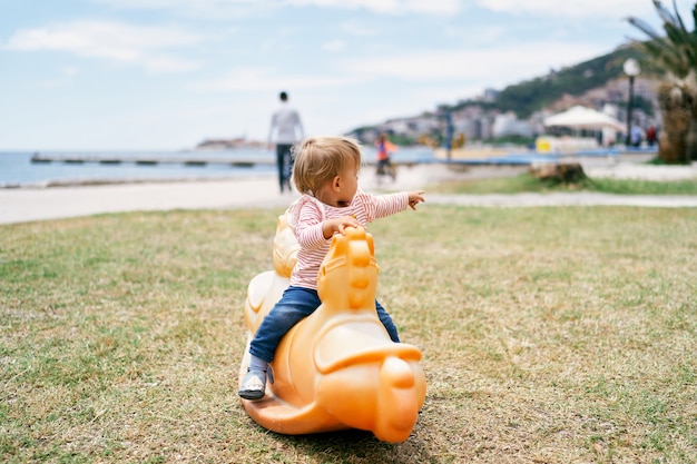 Niño sentado en un columpio en el patio de recreo en la playa