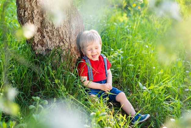 Niño sentado debajo de un árbol y descansando