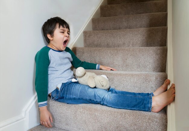 Foto niño sentado en la escalera en casa