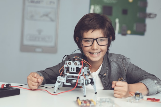 Niño sentado en el escritorio y construyendo robot en casa