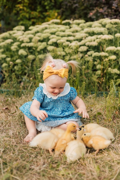 Niño sentado en la hierba junto a los patitos