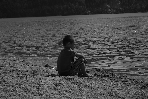 Foto niño sentado junto al lago