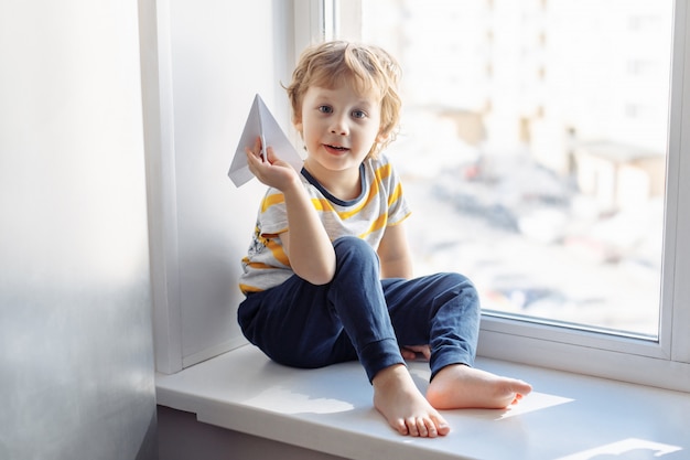 Niño sentado junto a la ventana.