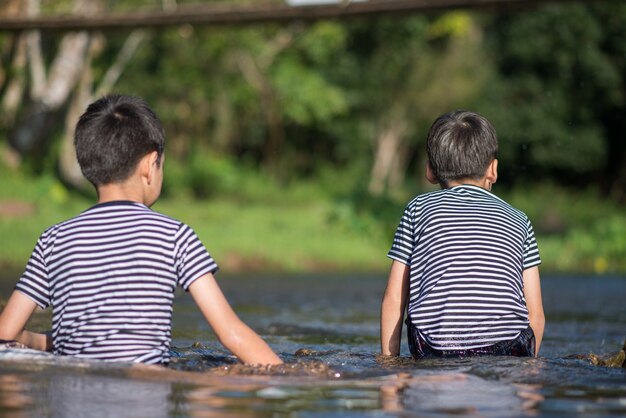 Niño sentado juntos en el canal del río