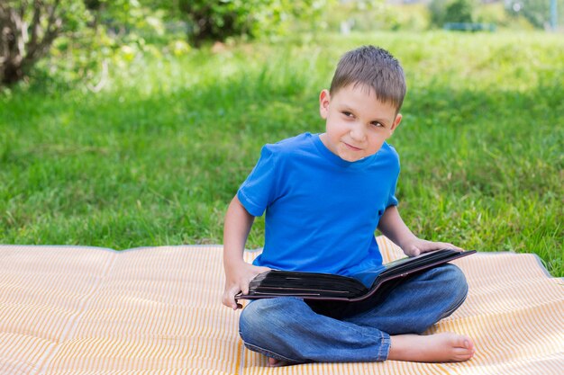 Foto niño sentado con un libro en el parque