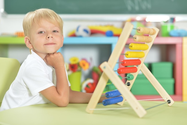 Niño sentado en la mesa y aprendiendo a usar ábaco