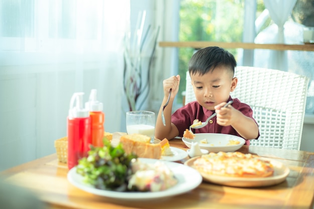 Niño sentado en la mesa, desayunando