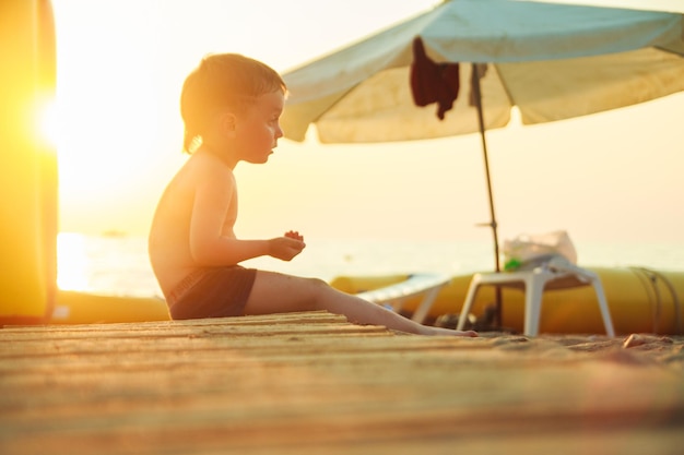 niño sentado en la playa al atardecer