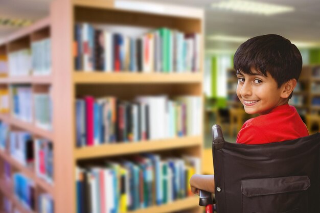 Foto niño sentado en silla de ruedas en la escuela contra volúmenes de libros en estantería en la biblioteca volúmenes de libros en estantería en la biblioteca de la universidad