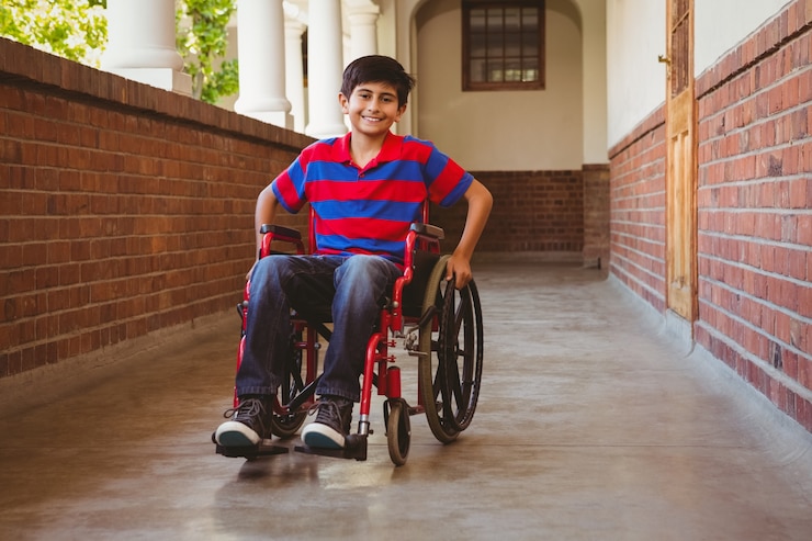 Foto niño sentado en silla de ruedas en el pasillo de la escuela