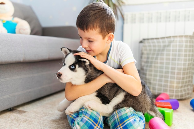 Un niño sentado en el suelo con su cachorro husky