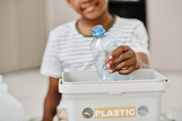 Niño separando plástico en un contenedor para reciclar