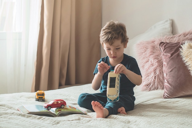 Un niño se sienta en una cama con juguetes.