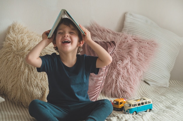 Un niño se sienta en una cama con un libro.