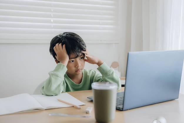un niño se sienta en un escritorio con una computadora portátil y una taza de café