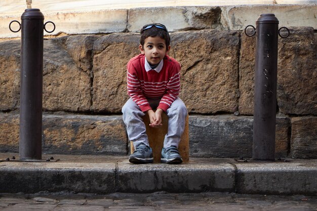 Un niño se sienta en una maleta con los números 009.