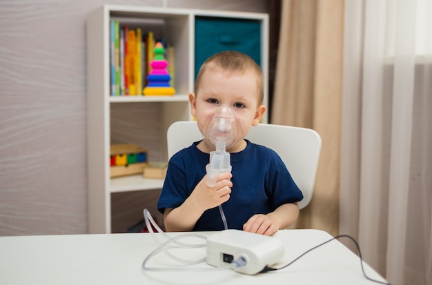 Niño se sienta en una mesa en una habitación e inhala a través de un nebulizador