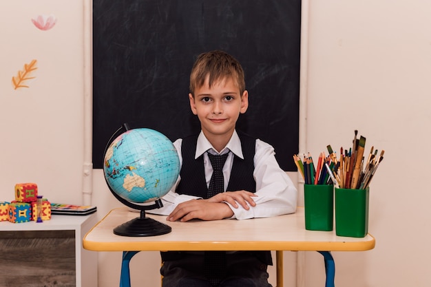 Un niño se sienta en un pupitre en una lección de geografía