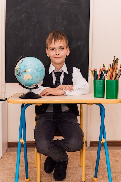 Un niño se sienta en un pupitre en una lección de geografía