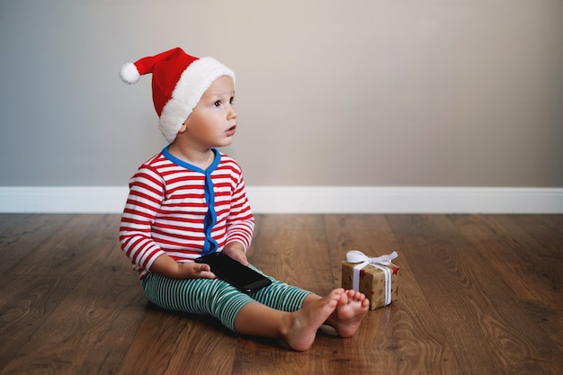 niño se sienta en el suelo junto al regalo con teléfono