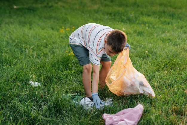 Un niño de siete años al atardecer se dedica a la recolección de basura en el parque Reciclaje de cuidado ambiental