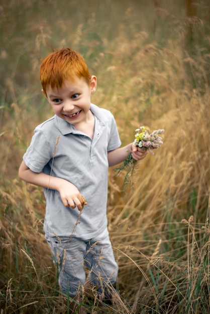 Un niño de siete años con cabello rojo con un ramo de flores silvestres en verano.