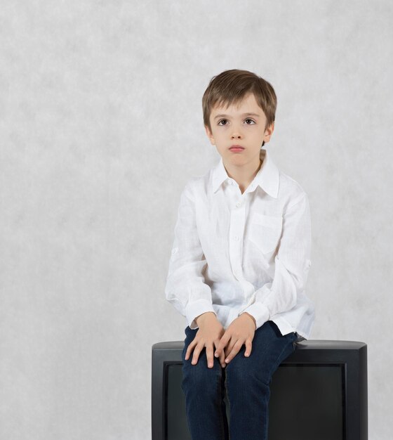 Niño de siete años y un televisor viejo. Espacio libre para un texto.