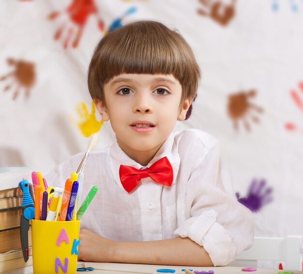 Niño de siete años vestido con camisa blanca con lazo rojo. De cerca