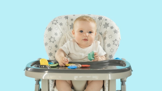 Un niño en una silla de alimentación juega con juguetes.