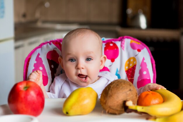 Foto niño en una silla alta comiendo fruta y sonriendo