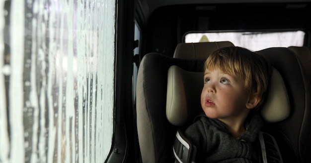 Niño en una silla de auto en el lavado de autos