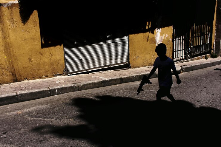 Foto niño silueta con una pistola de juguete caminando por la carretera durante un día soleado