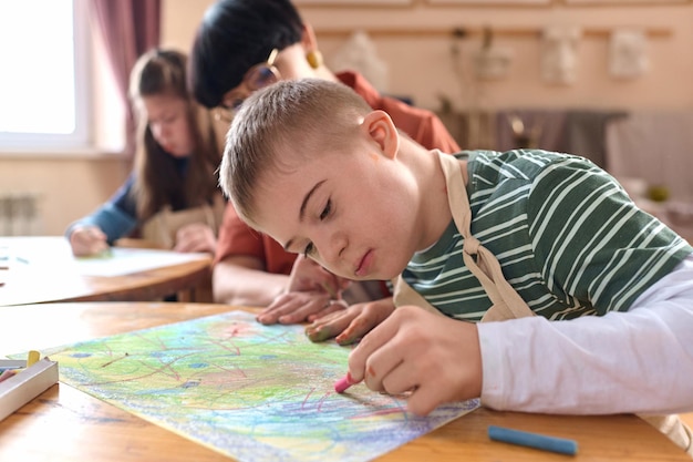 Foto un niño con síndrome de down pintando una imagen de cerca