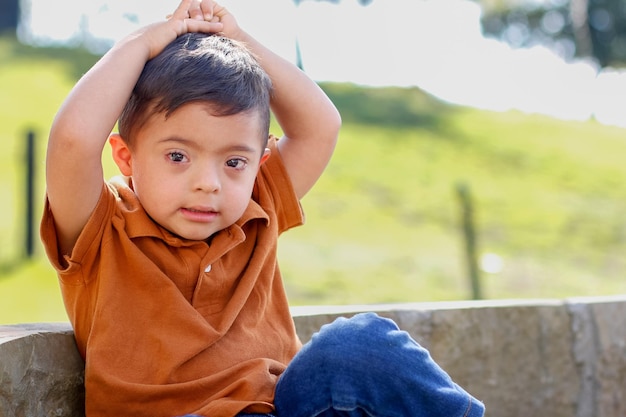 Niño con síndrome de Down sentado en un banco de piedra rodeado de naturaleza