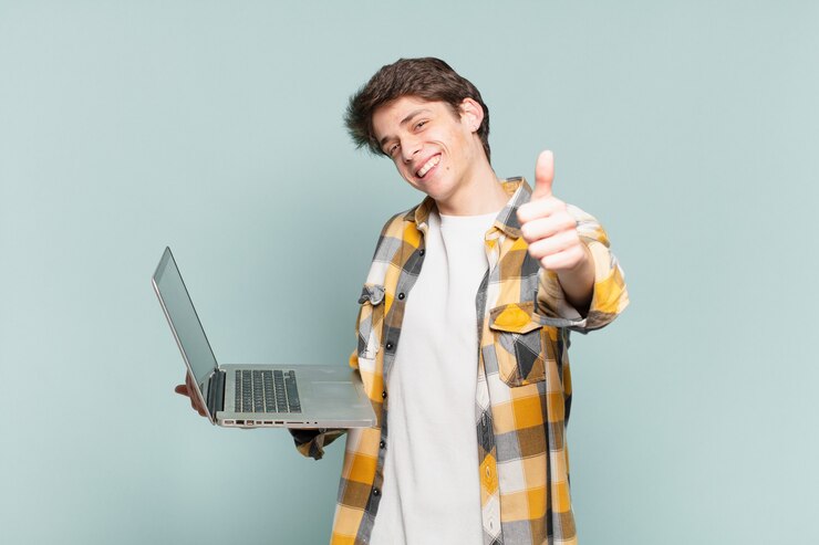 Foto niño sintiéndose orgulloso, despreocupado, seguro y feliz, sonriendo positivamente con los pulgares hacia arriba. concepto de laptop