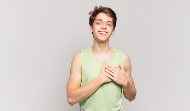 Niño sintiéndose romántico, feliz y enamorado, sonriendo alegremente y tomados de la mano cerca del corazón